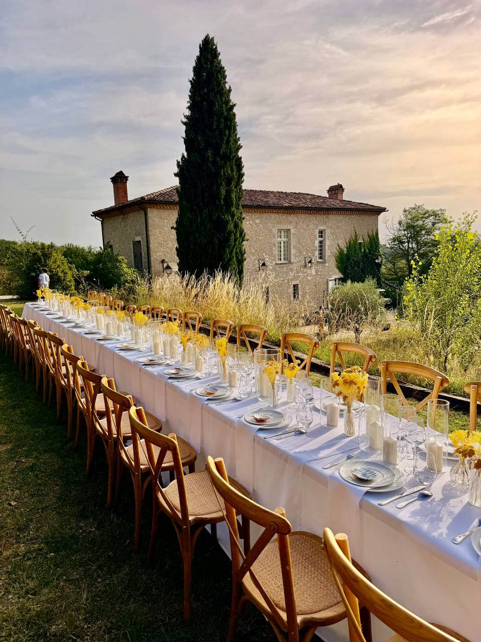 Long wedding table set at golden hour with the manor house behind, at Les Cazettes near Toulouse